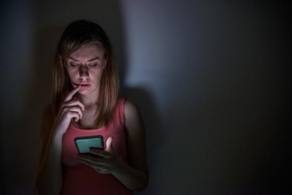 Una ragazza guarda il suo telefono nell'oscurità.